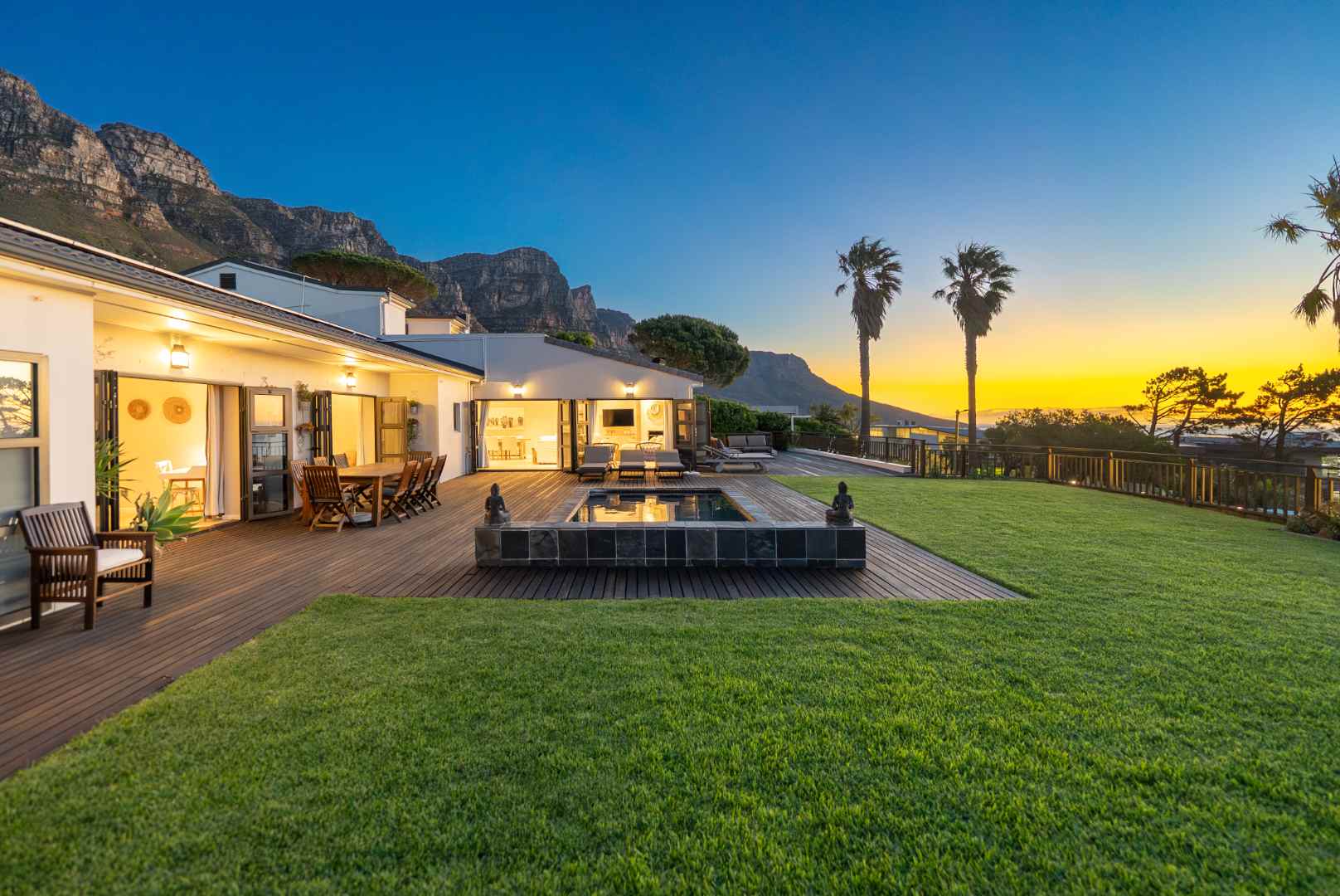 A Camps Bay home at twilight, lit pool and palms below the Twelve Apostles